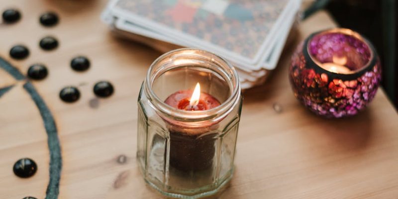 burning candles near tarot cards on table
